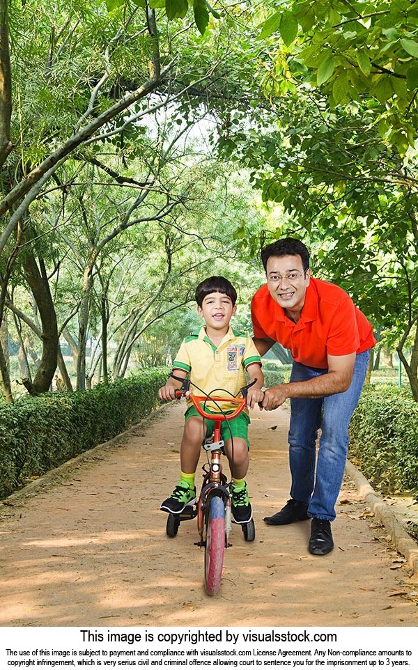 Father Helping Son Riding Bicycle Sidewalk