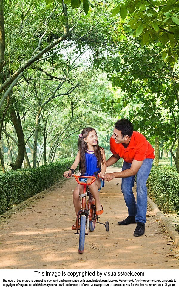 Father Helping Daughter Riding Bicycle Sidewalk
