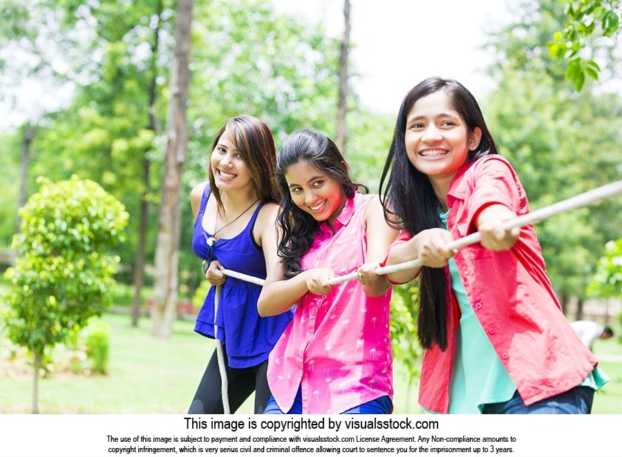 Teenager Friends Playing Tug Of War In Park