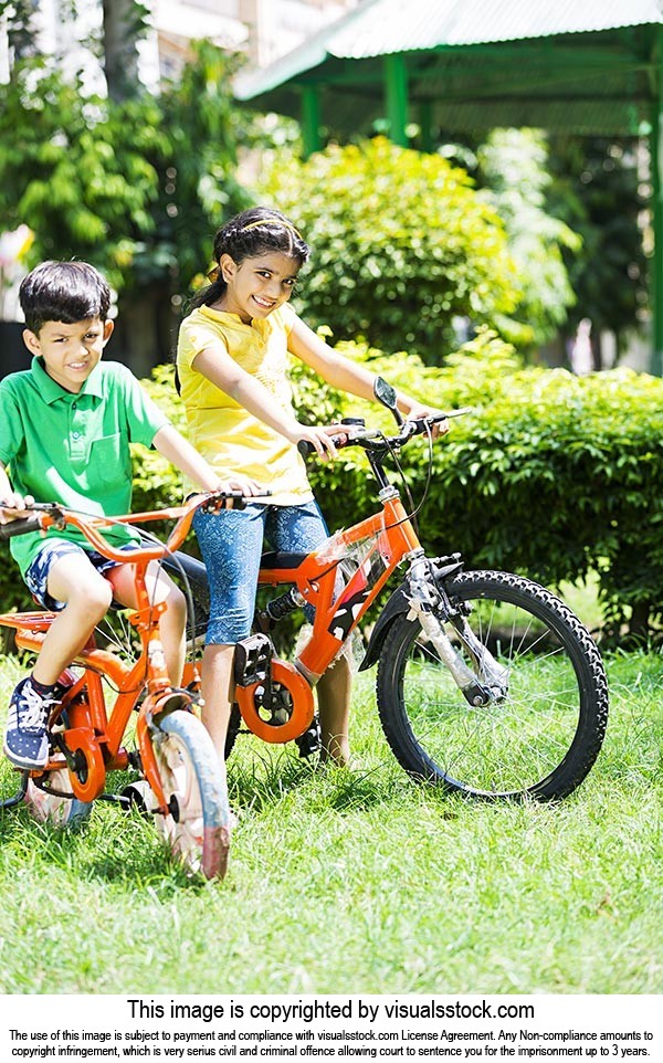 happy Two kids Friends Sitting On Bicycle Riding in sunny summer park