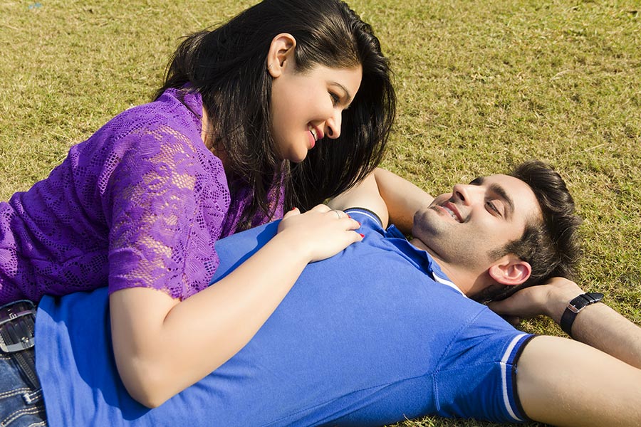 Happy Young Loving Couple in-love laying on-grass in summer park