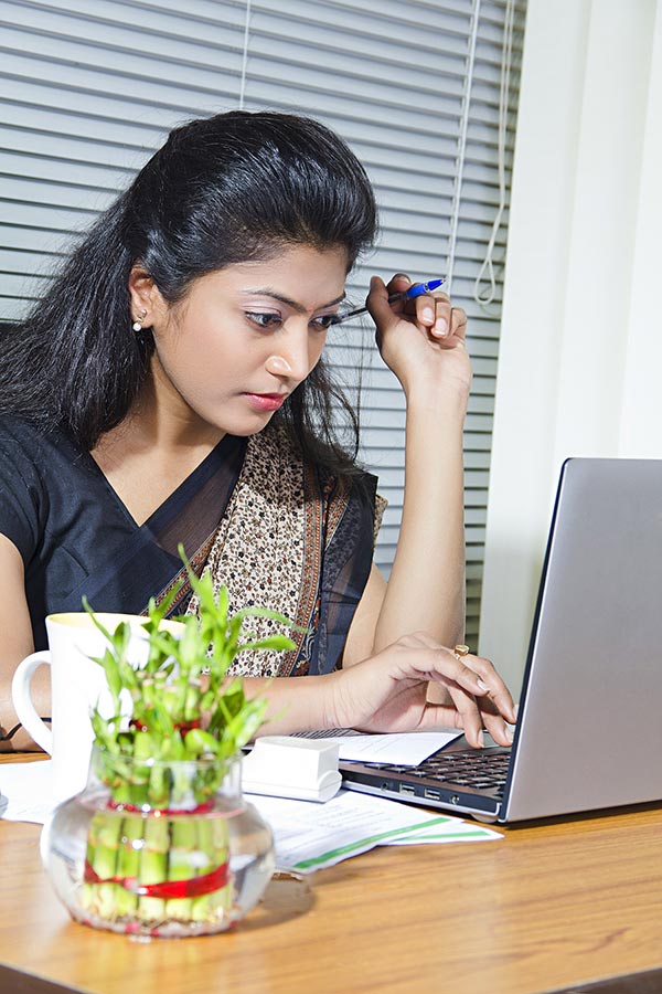 Serious Indian businesswoman working on laptop computer in-Office