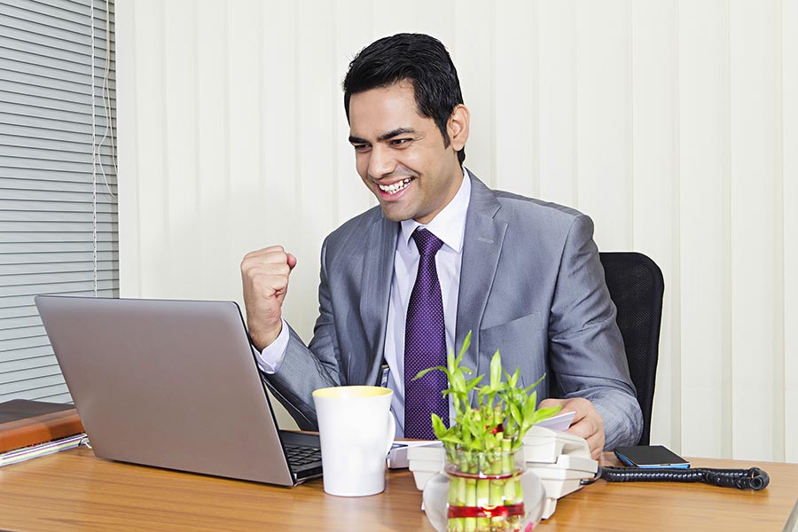 Businessman celebrating success looking at laptop screen with fist Office