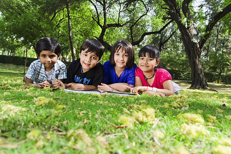 Four School Kids Students Studying Reading Book Lying-on-grass At-park