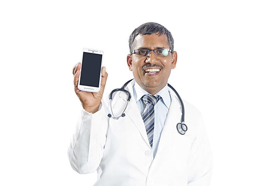 Indian Senior Man doctor smiling and showing a blank smart phone screen