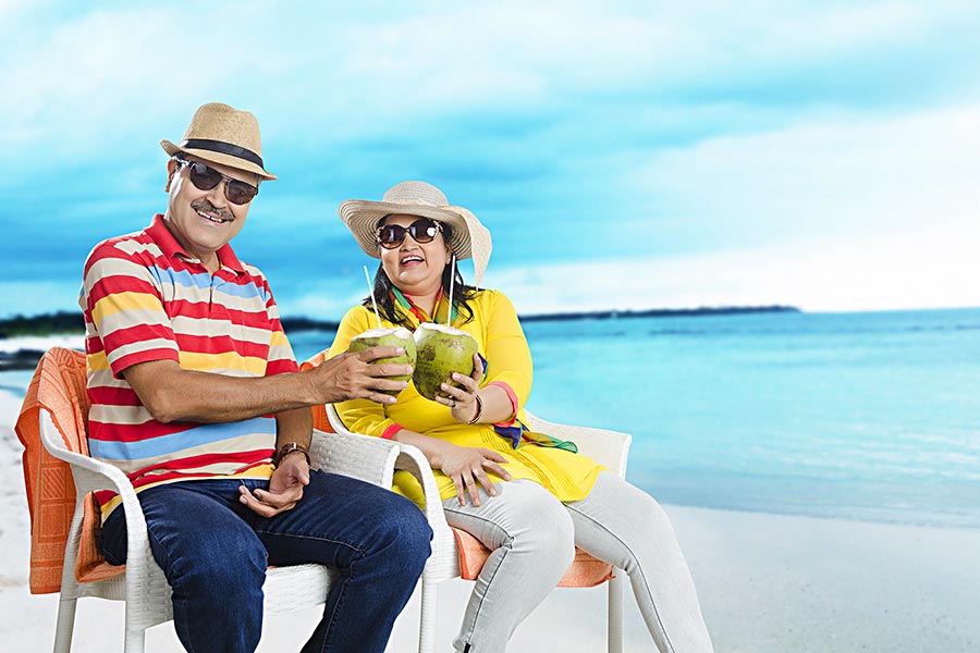 Indian Senior Couple Cheers and drink from coconuts On Beach