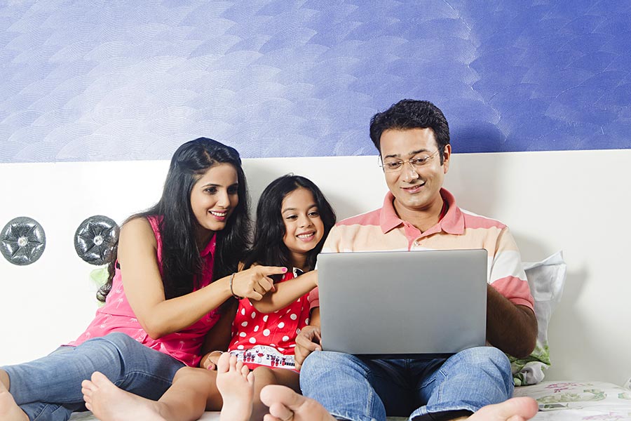 Indian Family Parents And Daughter Together Using laptop In Bed