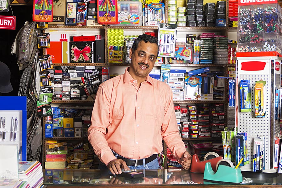 smiling-indian-shopkeeper-man-using-swap-machine-in-stationery-store