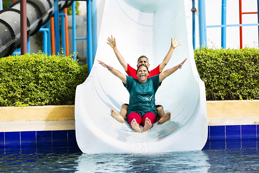 Happy Senior Couple sliding down slide Water park Fun Cheerful