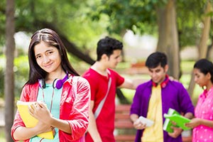 College girl holding books with students in park